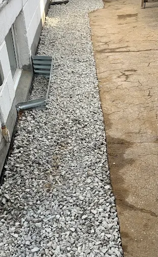 Finished gravel drainage strip beside a foundation wall and basement window