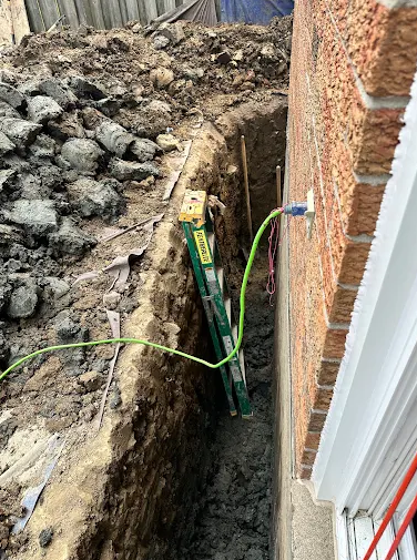 Exterior excavation alongside a residential foundation wall