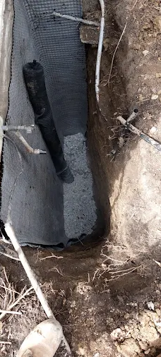 Foundation footing and drainage stone installed beside a basement wall